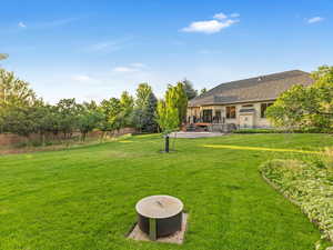View of green lawn with a wooden deck and a fire pit