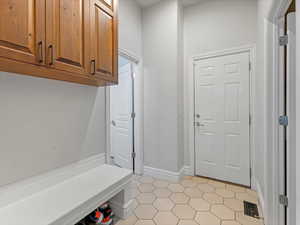Mudroom with tile floors, bench, and cabinets