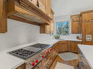 Kitchen with custom exhaust hood, 48" Wolf gas range, new windows, and tasteful backsplash