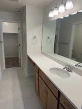 Full bathroom with a walk in closet, vanity, and light marble finish floors