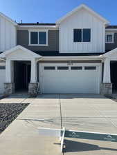 View of front facade featuring board and batten siding, stone siding, concrete driveway, and an attached garage