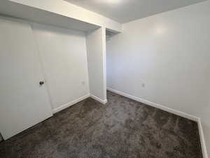 Spare room featuring dark carpet and baseboards