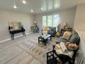 Living room featuring light wood-style floors, a textured ceiling, and recessed lighting