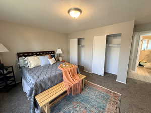 Carpeted bedroom featuring two closets and a textured ceiling