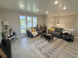 Living area featuring a textured ceiling, light wood-style floors, and recessed lighting