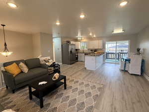 Living area with light wood-type flooring, a textured ceiling, and recessed lighting