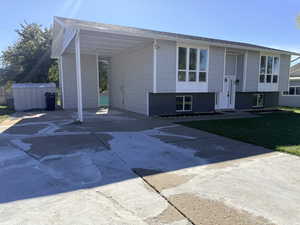 View of front facade with concrete driveway, a carport, and a front yard