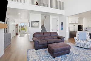 Living area featuring light wood-type flooring, recessed lighting, stairway, and a high ceiling