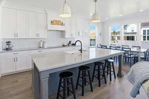 Kitchen with white cabinetry, a breakfast bar area, decorative backsplash, dark wood-style floors, and recessed lighting