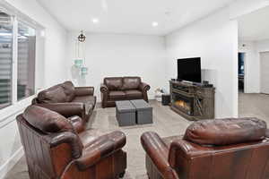 Living area with light colored carpet, a glass covered fireplace, and recessed lighting