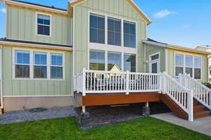 Back of property featuring board and batten siding, a wooden deck, and a yard