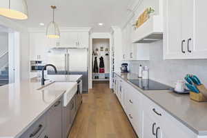 Kitchen featuring light wood-type flooring, hanging light fixtures, white cabinetry, premium range hood, and recessed lighting
