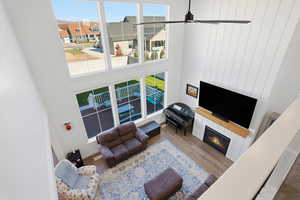 View of Living room from loft with healthy amount of natural light, a high ceiling, a glass covered fireplace, and wood finished floors