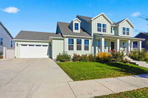 View of front facade featuring board and batten siding, a shingled roof, a front yard, and driveway