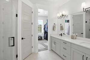 Bathroom featuring a shower stall, light tile patterned floors, double vanity, light colored carpet, and a walk in closet