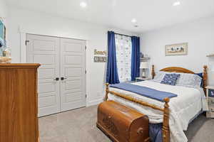 Bedroom with light colored carpet, a closet, and recessed lighting