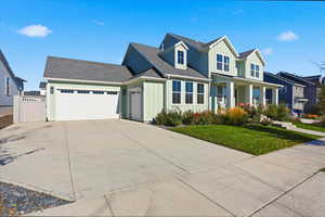 View of front facade featuring board and batten siding, roof with shingles, covered porch, and a front lawn
