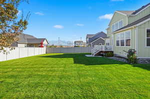 Fenced backyard with a residential view, a deck with mountain view, and stairway