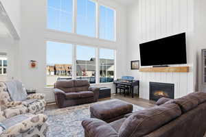 Living room with a large fireplace, wood finished floors, and a high ceiling
