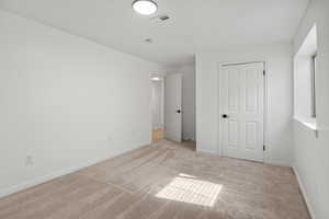 Unfurnished bedroom with light colored carpet and baseboards