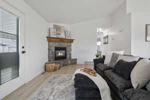 Living area featuring vaulted ceiling, a fireplace, and light wood-type flooring