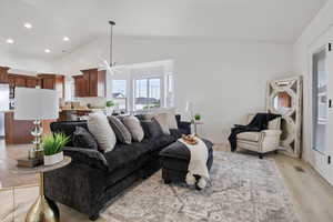 Living area with a chandelier, recessed lighting, high vaulted ceiling, and light wood-type flooring