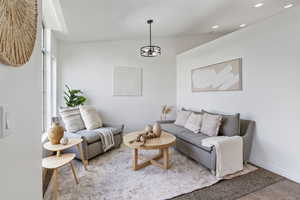Living room featuring vaulted ceiling, a chandelier, and recessed lighting