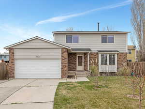 Traditional-style home with brick siding, driveway, and a garage