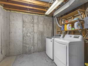 Laundry area featuring unfinished concrete flooring, independent washer and dryer, and electric panel