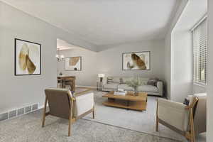 Carpeted living room featuring a chandelier and baseboards