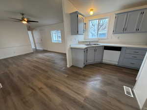 Kitchen featuring gray cabinetry, light countertops, dishwasher, and open floor plan