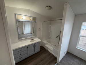 Bathroom with bathing tub / shower combination, vanity, and dark wood-type flooring