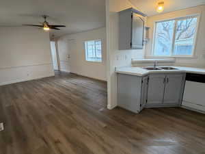 Kitchen with white dishwasher, light countertops, open shelves, dark wood-type flooring, and a ceiling fan