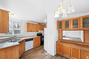Kitchen featuring decorative light fixtures, white appliances, light wood-style flooring, light countertops, and glass insert cabinets