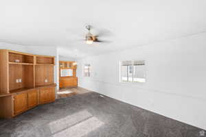 Unfurnished living room with carpet floors, lofted ceiling, a ceiling fan, and a chandelier