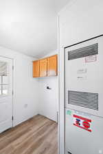 Washroom featuring a heating unit, light wood-type flooring, hookup for a washing machine, and cabinet space