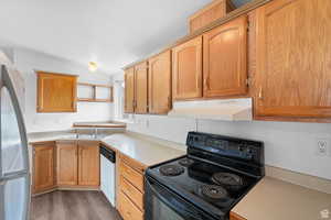 Kitchen with white appliances, light countertops, under cabinet range hood, light wood-style flooring, and lofted ceiling