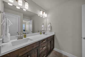 Full bathroom with double vanity and baseboards