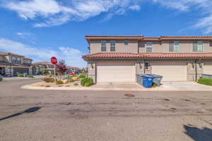 Mediterranean / spanish home with stucco siding, concrete driveway, a tiled roof, an attached garage, and a residential view
