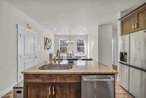 Kitchen with stainless steel appliances, dark brown cabinets, light stone countertops, recessed lighting, and a textured ceiling