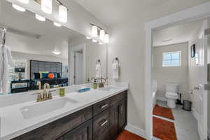 Bathroom featuring double vanity, ensuite bathroom, light tile patterned floors, and a bath