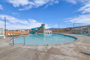 Community pool with a water slide and a patio area