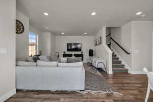 Living room with recessed lighting, stairs, and dark wood finished floors
