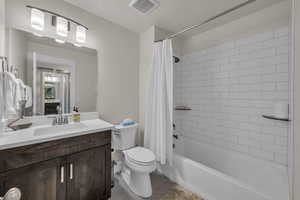 Full bath with shower / bath combo with shower curtain, vanity, and light tile patterned floors