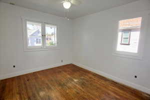 Spare room with dark wood finished floors, plenty of natural light, and a ceiling fan