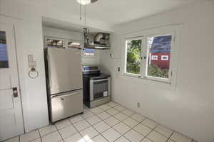 Kitchen with stainless steel appliances, light tile patterned floors, under cabinet range hood, and a ceiling fan