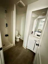 Bathroom with dark wood-style floors, vanity, and a stall shower