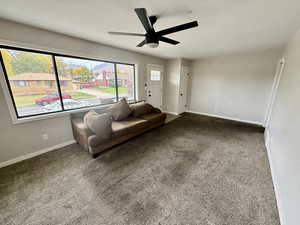 Carpeted living area with baseboards and a ceiling fan