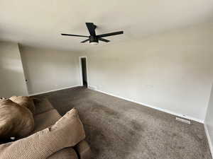 Carpeted living room featuring baseboards and ceiling fan