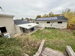 Back of property featuring a patio area, roof mounted solar panels, brick siding, and roof with shingles